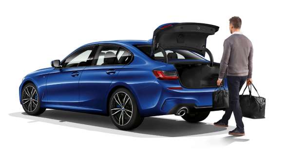 BMW 3. seeria Sedan, automaatne pagasiluugi avamine. Kolm neljandikku tagantvaates seisev BMW 3. seeria Sedan, juht jalaga automaatset pagasiluuki avamas.
