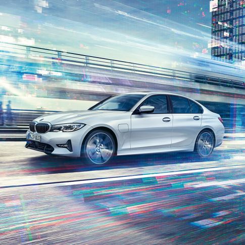BMW 3. seeria Sedan, sõitev BMW 3. seeria Sedan 330e ikülgvaates. Sõitev BMW 3. seeria Sedan 330e iPerformance eestvaates linna taustal.
