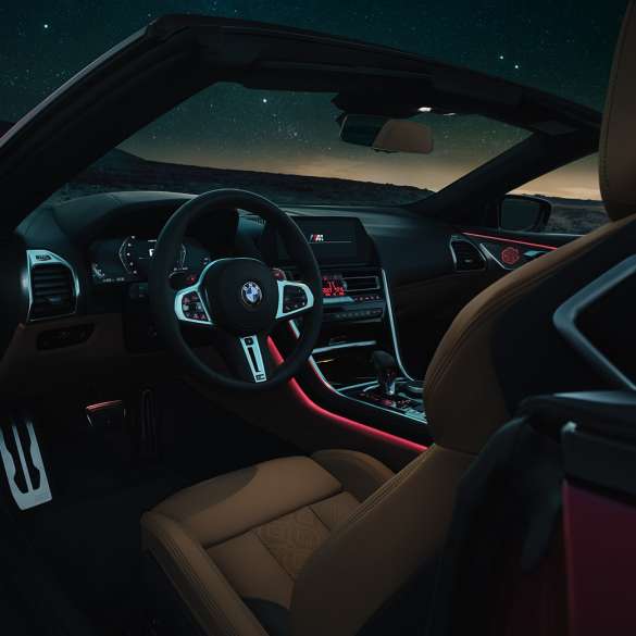 BMW M8 Competition Cabrio, juhikoht. BMW M8 Competition Cabrio, nahkkattega M-rooli ja punase salongivalgustusega juhikoht öösel.