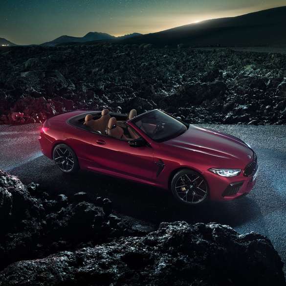 BMW M8 Competition Cabrio, kolm neljandikku külgvaade. BMW M8 Competition Cabrio toonis Motegi Red metallik, avatud pehme katusega, kolm neljandikku külgvaade, öösel asfaldil seismas.