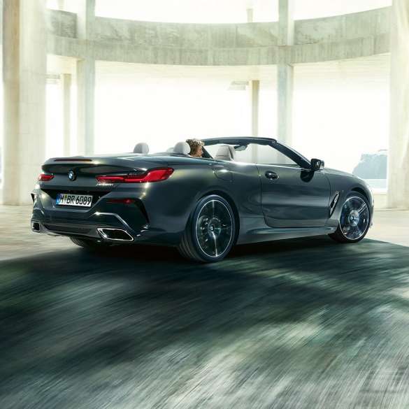 BMW M850i xDrive Cabrio, kolm neljandikku tagantvaade. BMW M850i xDrive Cabrio toonis Dravit Grey metallik, avatud pehme katusega, kolm neljandikku tagantvaade, sõitmas läbi betoonehitise.