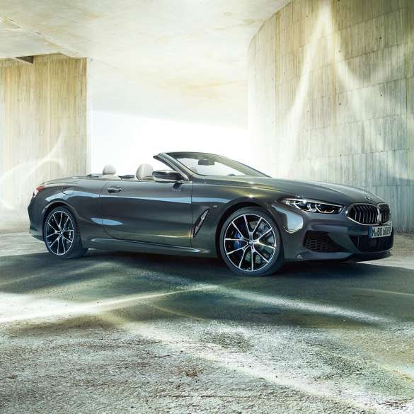BMW M850i xDrive Cabrio, kolm neljandikku külgvaade. BMW M850i xDrive Cabrio toonis Dravit Grey metallik, avatud pehme katusega, kolm neljandikku külgvaade, seismas betoonehitise ees.