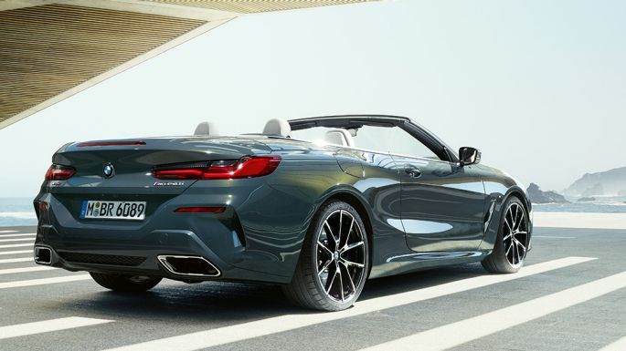 BMW M850i xDrive Cabrio, kolm neljandikku tagantvaade. BMW M850i xDrive Cabrio toonis Dravit Grey metallik, avatud pehme katusega, kolm neljandikku tagantvaade, parkimas vaatega ookeanile.