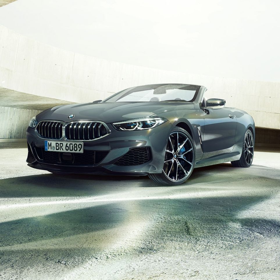 BMW M850i xDrive Cabrio, kolm neljandikku eestvaade. BMW M850i xDrive Cabrio toonis Dravit Grey metallik, avatud pehme katusega, kolm neljandikku eestvaade, seismas betoonehitises.