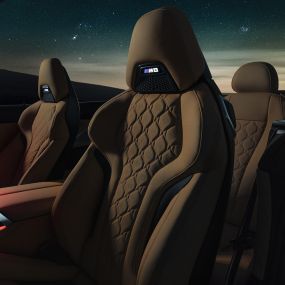 M-sportistmed 'Merino' nahkkattega. BMW M8 Competition Cabrio, avatud pehme katusega tähistaeva all, salong 'Merino' nahkkattega M-sportistmete ja punase salongivalgustusega.