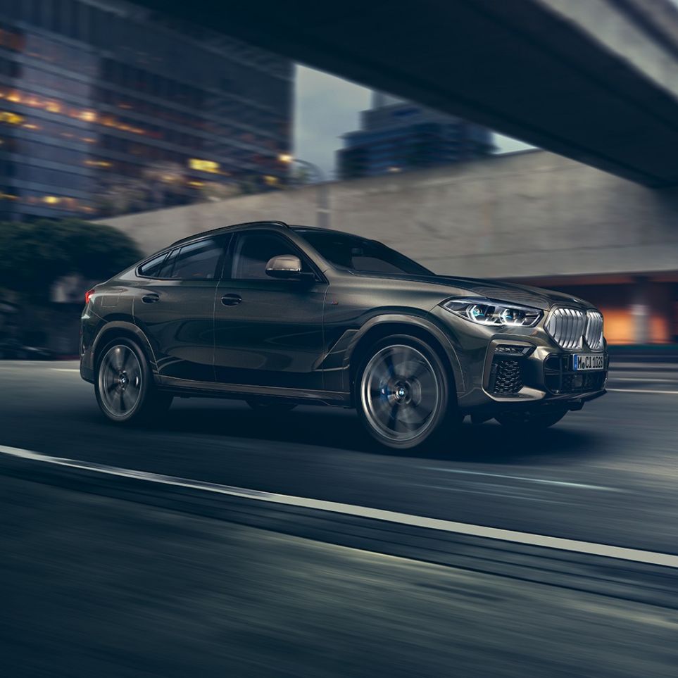 BMW X6 sõitmas. BMW X6 in three-quarter front perspective driving in front of an urban setting.