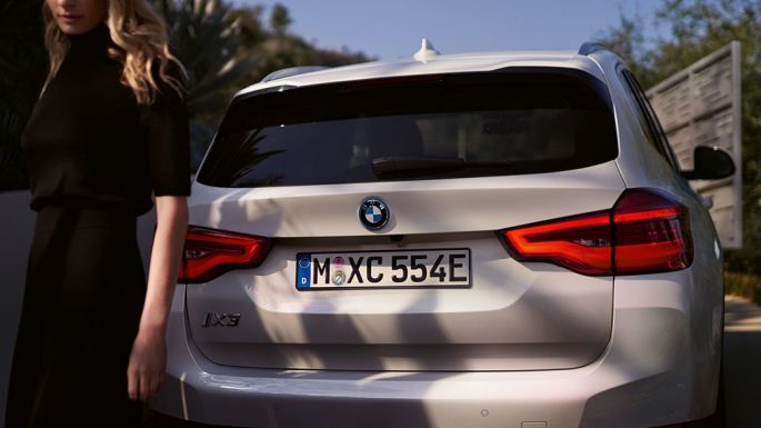 BMW iX3 G08 tagantvaade BMW i-spetsiifilisele difuusorile koos naisega BMW iX3 G08 2020 Mineral White metallik tagantvaade BMW i-spetsiifilisele difuusorile koos naisega