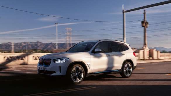 BMW iX3 G08, kohanduv M-vedrustus, tänaval sõites BMW iX3 G08 2020 Mineral White metallik, kohanduv M-vedrustus, kolm neljandikku eestvaade tänaval sõites
