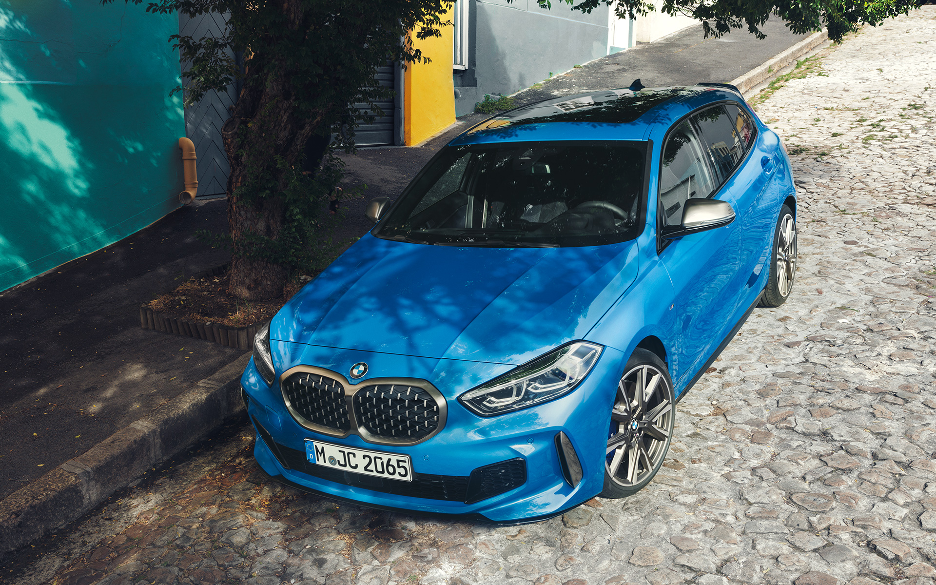 BMW 1. seeria M135i F40 värvitoonis Misano Blue metallik, kolm neljandiku eestvaade, parkimas tee ääres, ülaltvaates