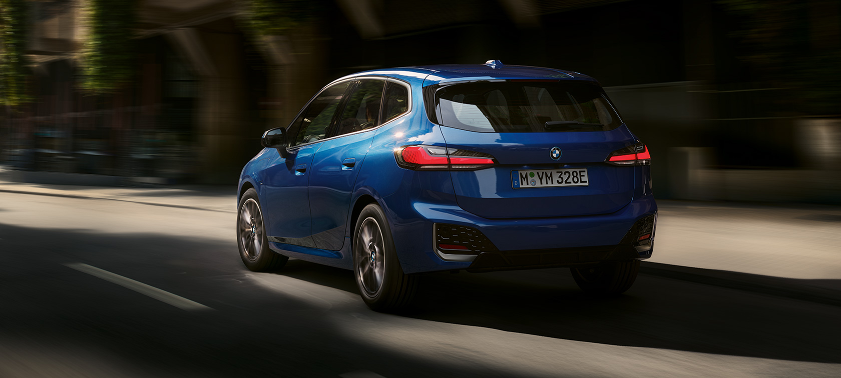 BMW 2. seeria Active Tourer 230e pistikhübriid U06 2021 sõitmas linnas BMW 2. seeria Active Tourer 230e pistikhübriid U06 2021 M Portimao Blue metallik, kolm neljandikku tagantvaade sõites linnas