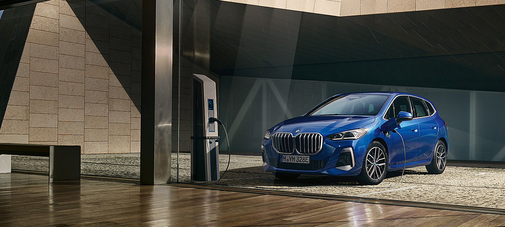 BMW 2. seeria Active Tourer 230e pistikhübriid U06 2021 M Portimao Blue metallik, kolm neljandikku eestvaade laadimisjaamas