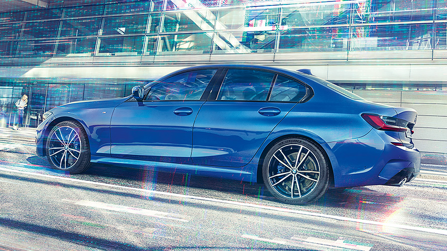BMW 3. seeria Sedaan (G20) päevasel ajal klaasist hoone ees. BMW 3. seeria Sedaan (G20) Portimao Blue, staatiline külgvaade päevasel ajal klaasist hoone ees.