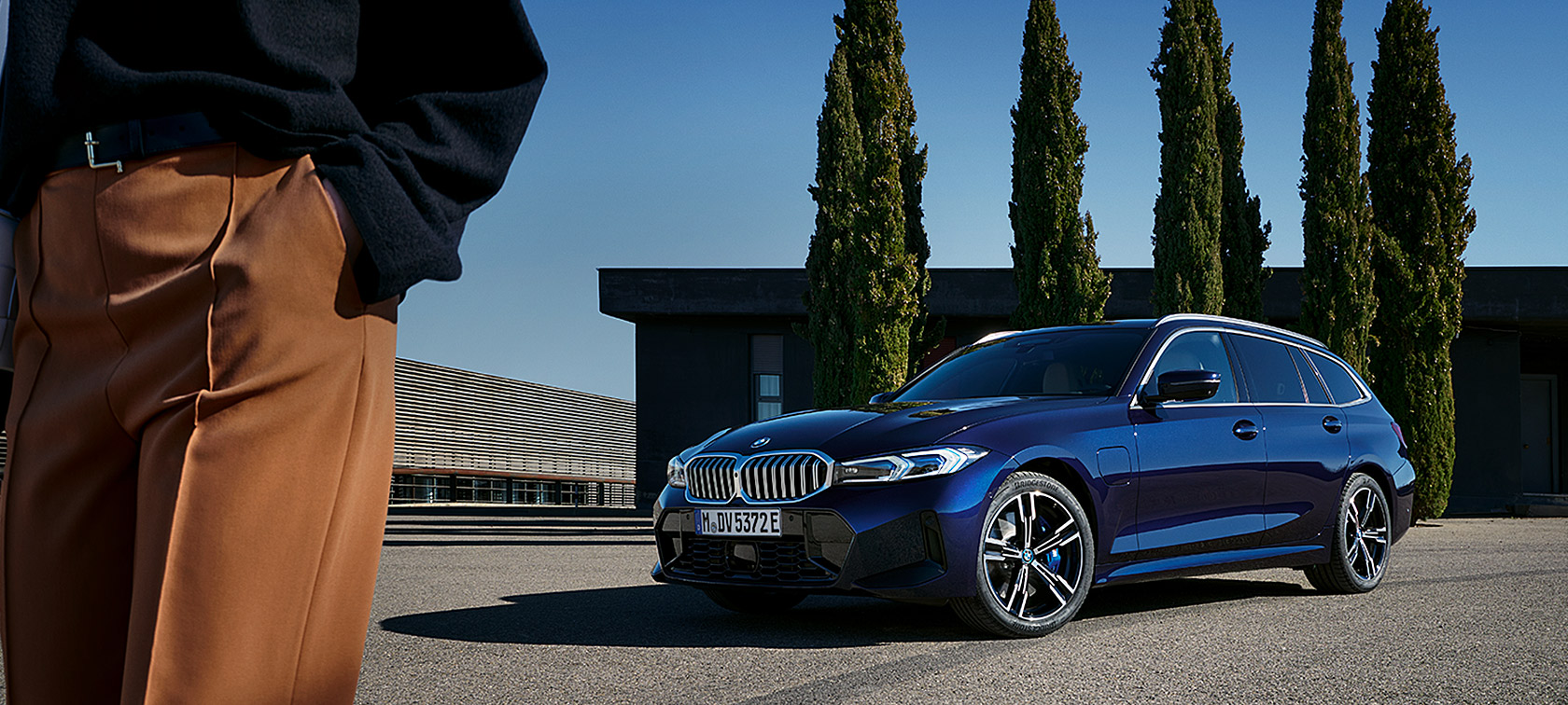 BMW 3. seeria Touring LCI G21, Tanzanite Blue II, kolm neljandikku eestvaade puude ees seistes