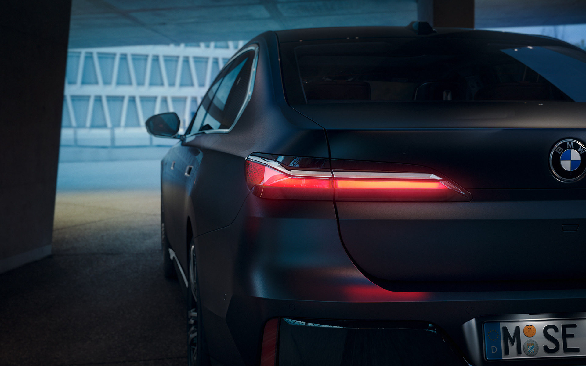 BMW 7. seeria Sedaan G70 ICE 740i M-sportpakett Frozen Deep Grey metallik, tagantvaade BMW 7. seeria Sedaan G70 ICE 740i M-sportpakett Frozen Deep Grey metallik, tagantvaade tunnelis punase helendava tagatulega
