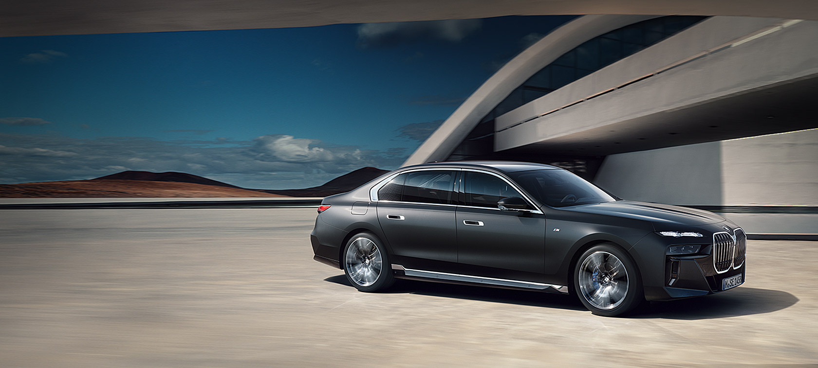 BMW 7. seeria Sedaan G70 ICE M-sportpakett, Frozen Deep Grey metallik, kolm neljandikku eestvaade, seismas hoone ees