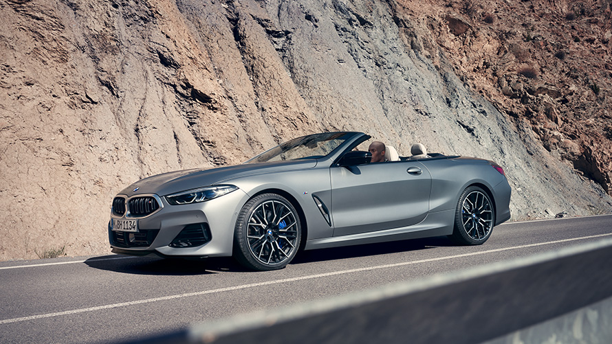 BMW 8. seeria Cabrio G14 LCI Facelift 2022 sõitmas avatud katusega mäekülje ees BMW 8. seeria Cabrio G14 LCI Facelift 2022 BMW Individual Frozen Pure Grey metallik sõitmas avatud katusega mäekülje ees, külgvaade