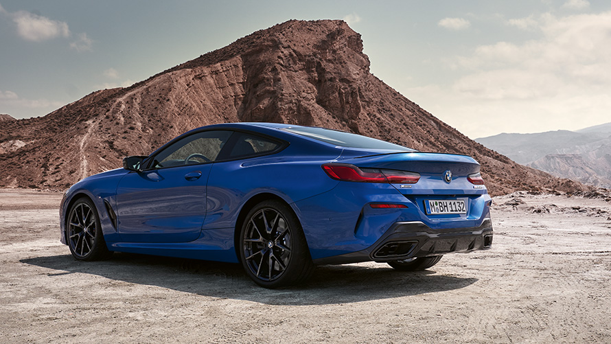 BMW 8. seeria Coupé M-sportpakett G15 LCI Facelift 2022 kolm neljandikku tagantvaade BMW 8. seeria kupee M-sportpakett G15 LCI Facelift 2022 M Portimao Blue metallik kolm neljandikku tagantvaade seistes kivide ees