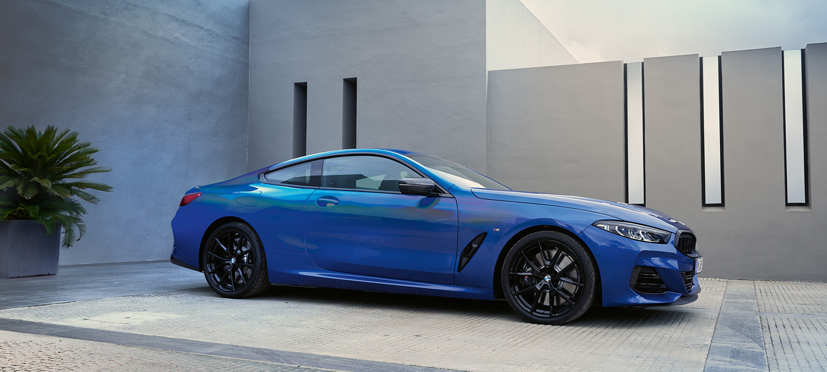 BMW 8. seeria kupee G15 LCI Facelift 2022 M Portimao Blue metallik külgvaade seistes hoone seina ees