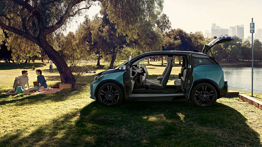 BMW i3 2018 pargis BMW i3 I01 2018 Jucaro Beige metallikvärv koos Frozen Grey metallikviimistlusega, külgvaade avatud ustega pargis
