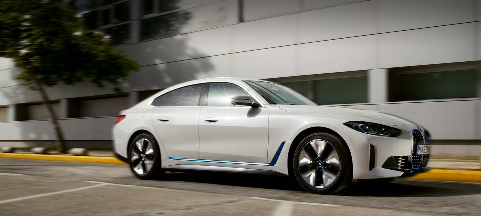 BMW i4 eDrive40 G26 2021 kolm-neljandikku külgvaates hoone ees sõitmas BMW i4 eDrive40 G26 2021 kolm-neljandikku külgvaates hoone ees sõitmas