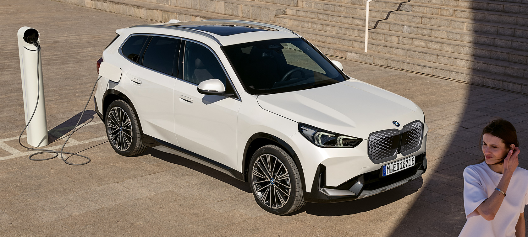 BMW iX1 U11 elektriauto, külgvaade, laadimine BMW iX1 U11 elektriauto 2022, Mineral White metallik, kaks kolmandikku külgvaade, laadimine, trepid