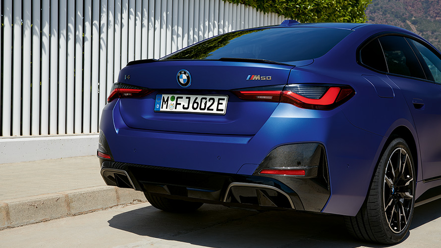 BMW i4 M50 G26 2021, BMW Individual Frozen Portimao Blue metallik, kolm neljandikku tagantvaade, seismas valge aia &auml;&auml;res