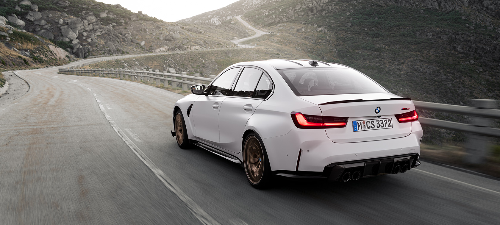 BMW M3 CS G80, kolm neljandikku tagantvaade sõites BMW M3 CS G80, kolm neljandikku tagantvaade mägiteel sõites