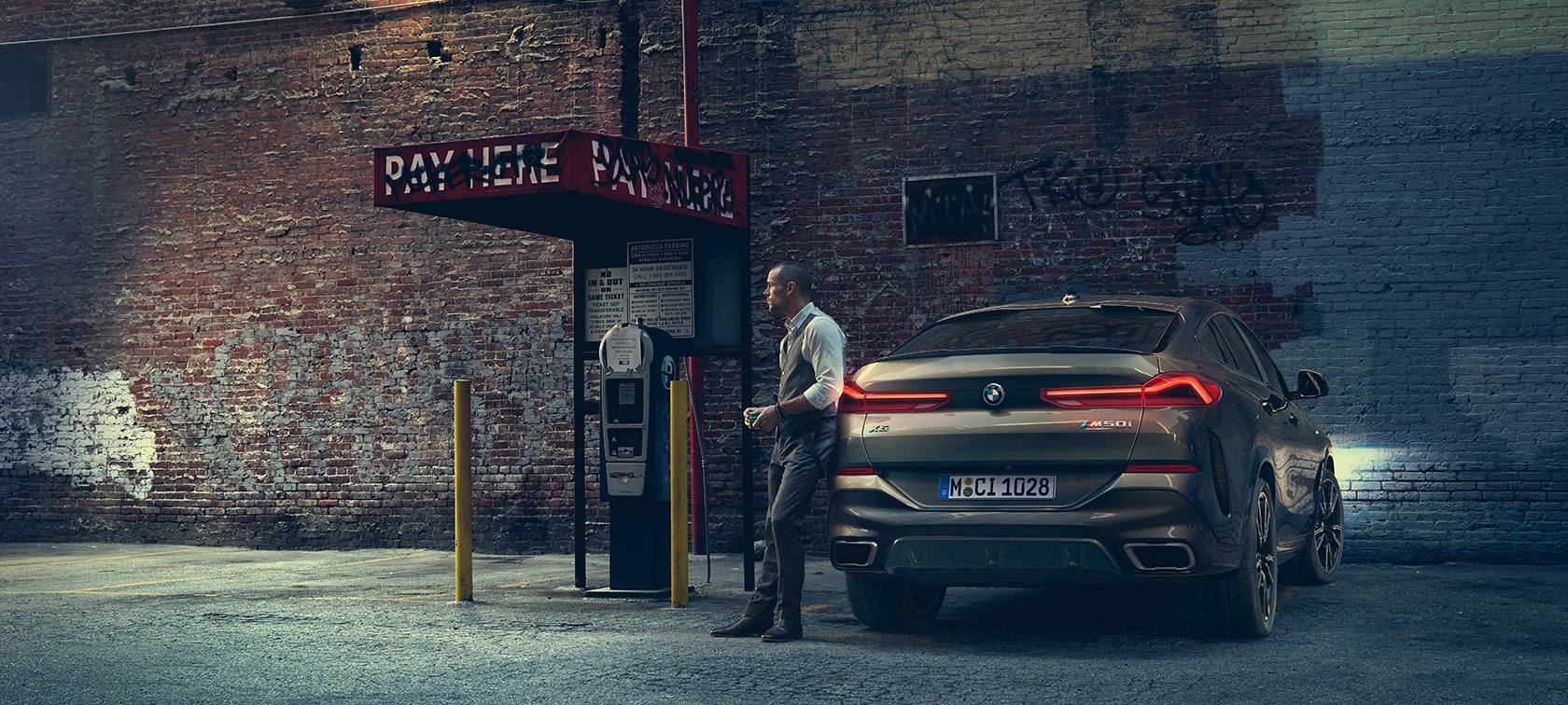 BMW X6 M50i tagantvaade. Mees toetumas BMW X6 M50i tagaosale.