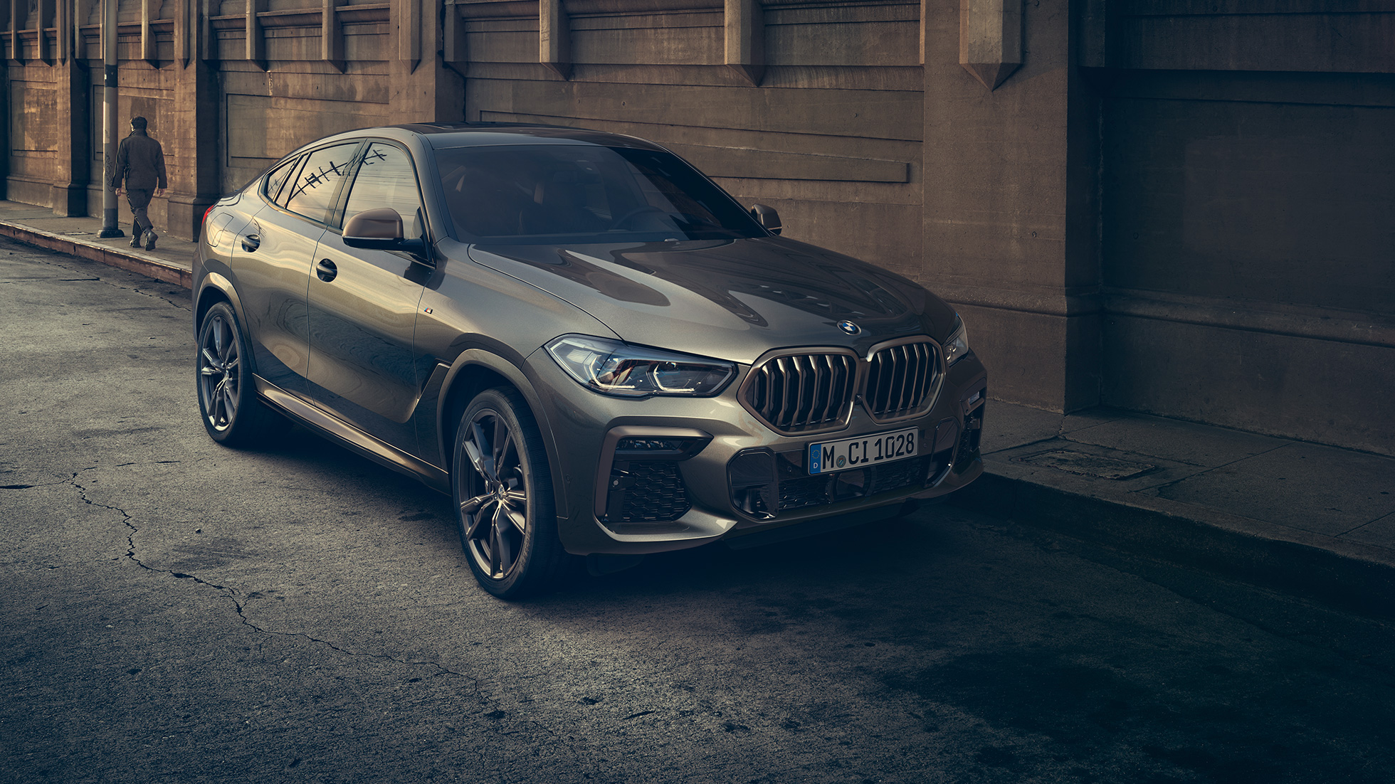 BMW X6 M50i paigal seismas. BMW X6 M50i in three-quarter front perspective standing in front of an urban setting.