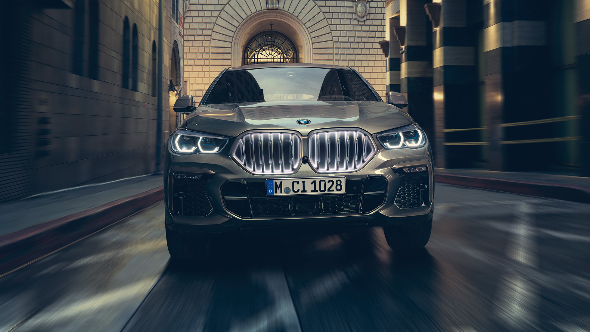 BMW X6 M50i neerukujuline iluvõre ’Iconic Glow‘. BMW X6 M50i in front perspective in front of an urban setting.