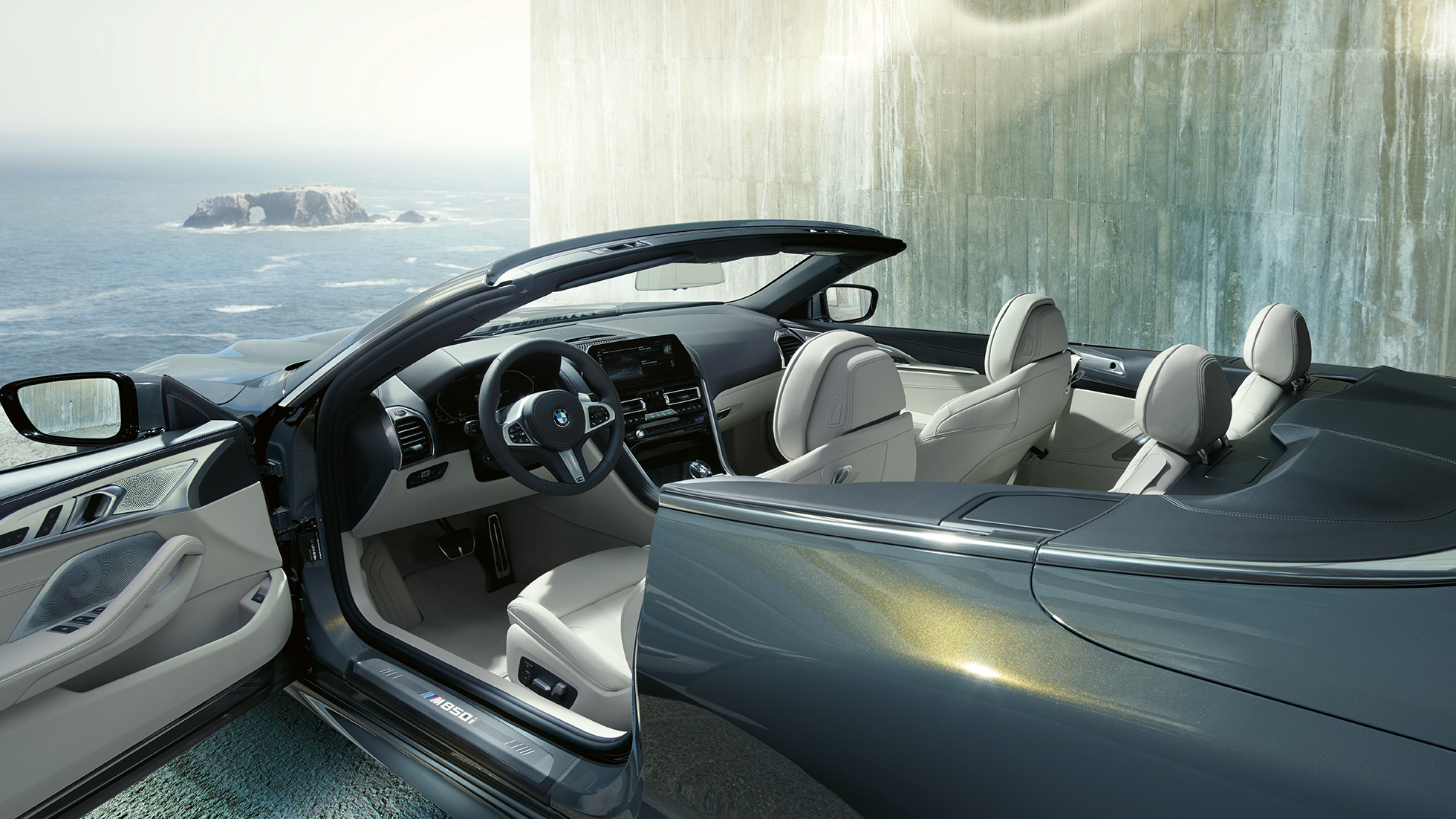 BMW M850i xDrive Cabrio, salong. BMW M850i xDrive Cabrio toonis Dravit Grey metallik, avatud pehme katusega, salong koos nahkkattega M-rooliga ja BMW Individuali nahkpolstriga 'Merino' Ivory White.
