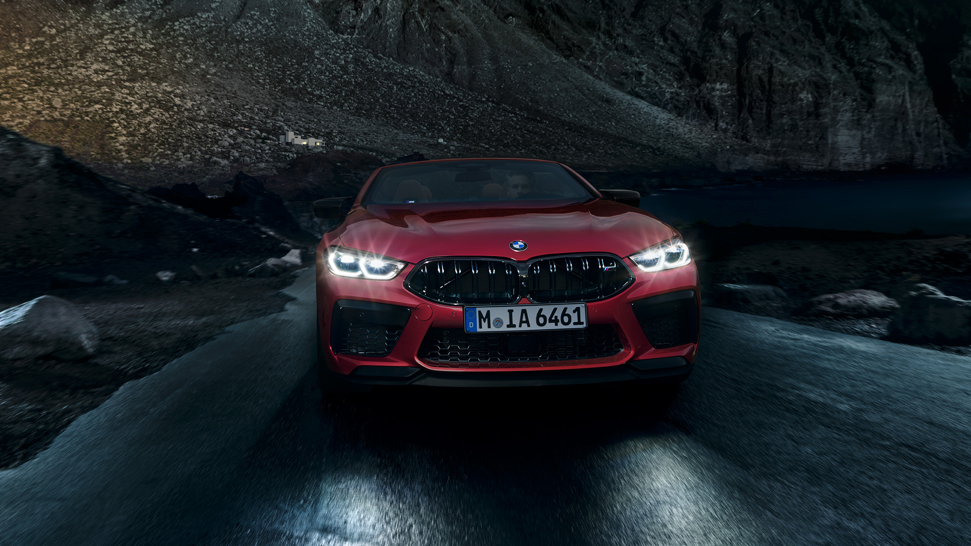 BMW M8 Competition Cabrio, eestvaade. BMW M8 Competition Cabrio toonis Motegi Red metallik, säravate esituledega, eestvaade, öösel sõitmas.