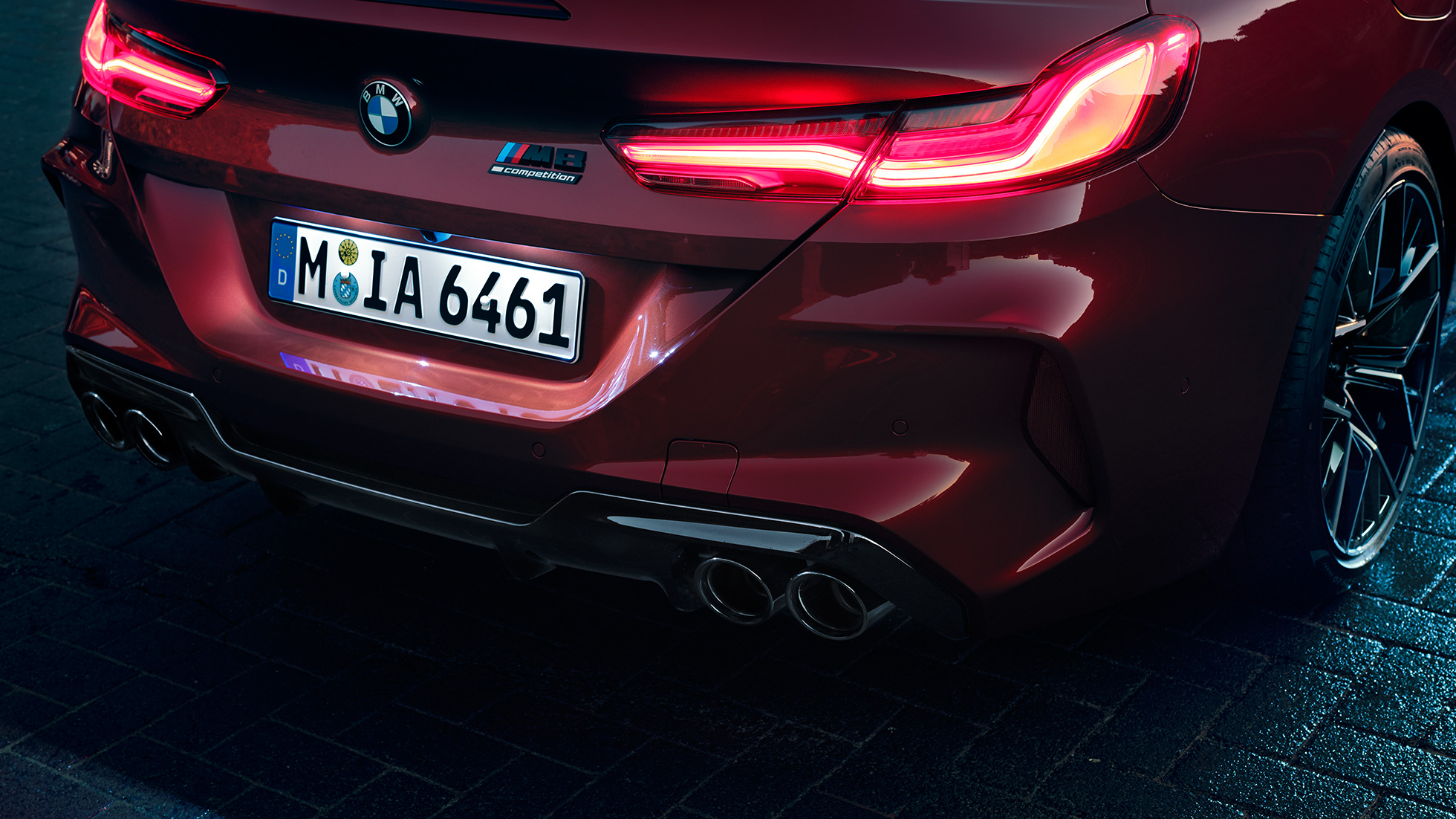 BMW M8 Competition Cabrio, tagaosa lähivaade. BMW M8 Competition Cabrio toonis Motegi Red metallik, lähivaade tagaosast koos LED-tagatulede ja M8 Competitioni embleemiga.