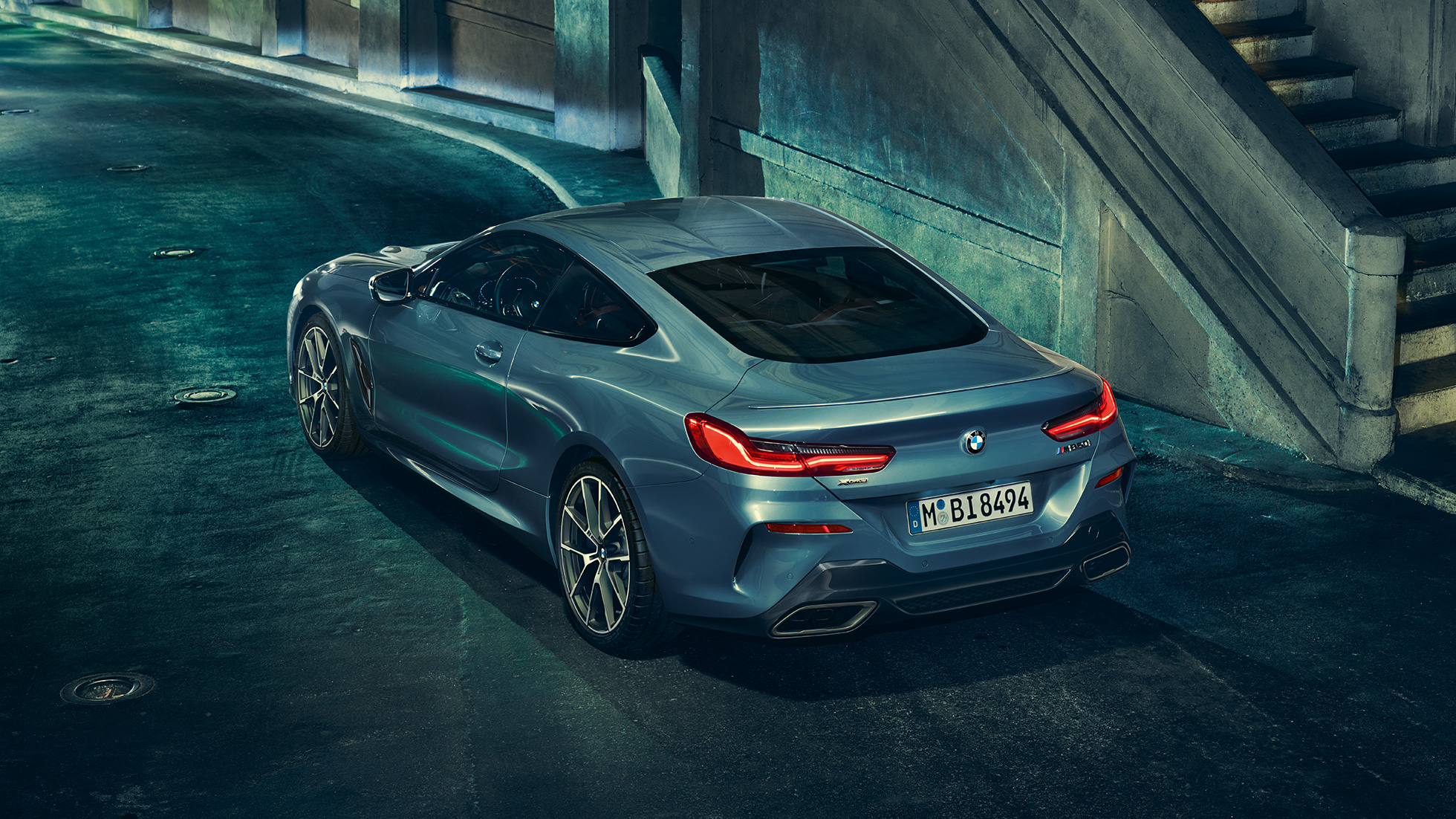 BMW M850i xDrive Coupé, kolm neljandikku tagantvaade vasakult. BMW M850i xDrive Coupé toonis Barcelona Blue metallik, kolm neljandikku tagantvaade vasakult, seismas öösel.