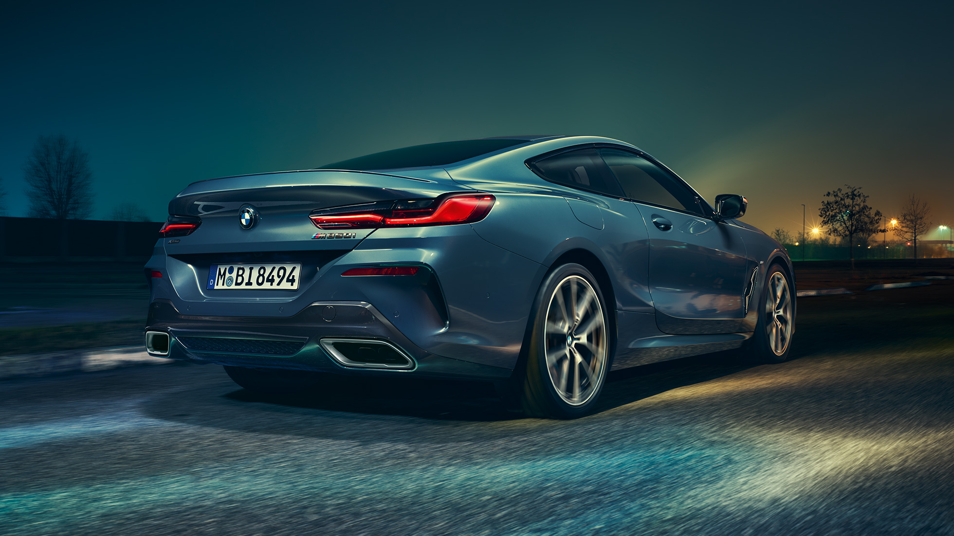 BMW M850i xDrive Coupé, tagantvaade. BMW M850i xDrive Coupé toonis Barcelona Blue metallik, tagantvaade, sõitmas öösel.