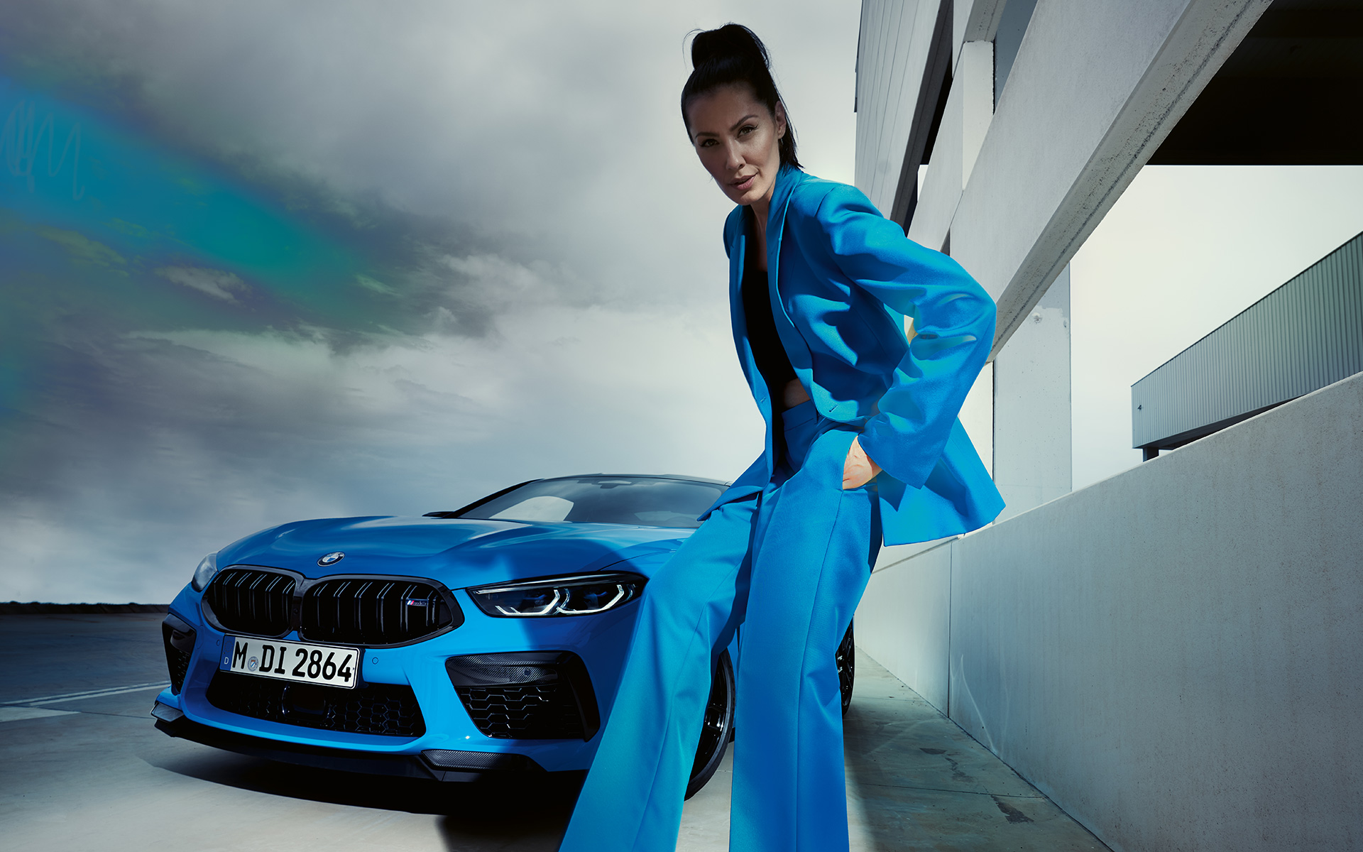 BMW M8 Competition Coupé F92 LCI Facelift 2022 Daytona Beach Blue uni kolm neljandikku eestvaade sinises pükskostüümis naismodelliga