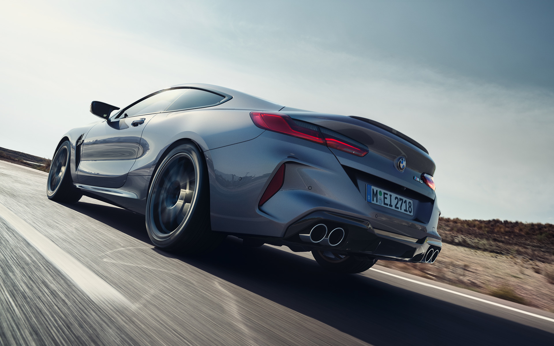 BMW M8 Coupé F92 LCI Facelift 2022 Skyscraper Grey metallik, sõites maanteel, kolm neljandikku tagantvaade, madala nurga võte