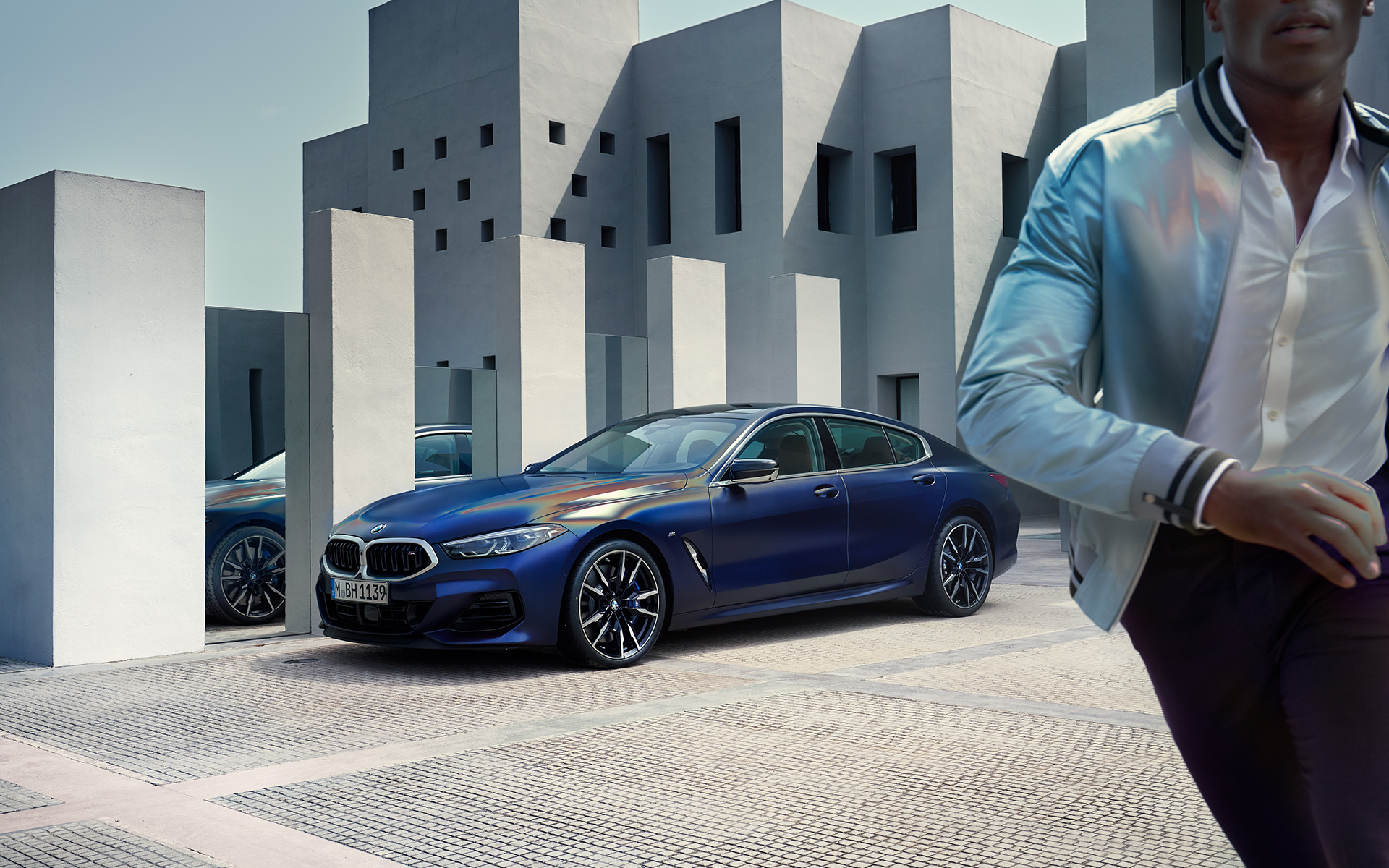 BMW M850i xDrive Gran Coupé G16 LCI Facelift 2022 kolm neljandikku eestvaade BMW M850i xDrive Gran Coupé G16 LCI Facelift 2022 BMW Individual Frozen Tanzanite Blue metallik kolm neljandikku eestvaade seistes koos meesmodelliga esiplaanil