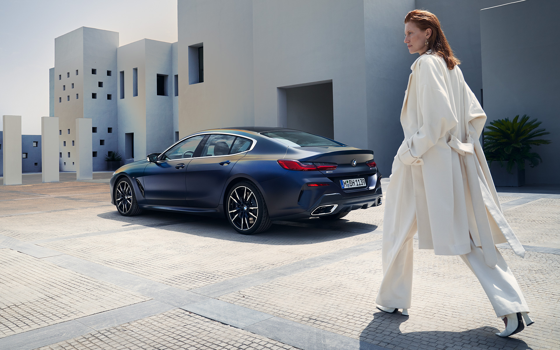 BMW M850i xDrive Gran Coupé G16 LCI Facelift 2022 külgvaade naismodelliga BMW M850i xDrive Gran Coupé G16 LCI Facelift 2022 BMW Individual Frozen Tanzanite Blue metallik, kolm neljandikku tagantvaade koos naismodelliga