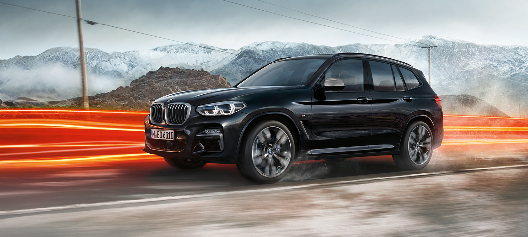 BMW X3 M40i ja BMW X3 M40d, külgvaade. Black Sapphire metallikvärvi BMW X3 M40i ja BMW X3 M40d, sõitmas, välisilme, külgvaade valgusribadega mägimaastiku taustal.