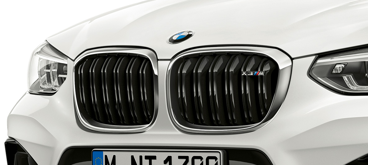 BMW X3 M, neerukujuline M-iluvõre. Alpine White värvi BMW X3 M, välisilme, esiosa, neerukujuline M-iluvõre koos kroomitud rõhujoonte ja mudelitähisega.