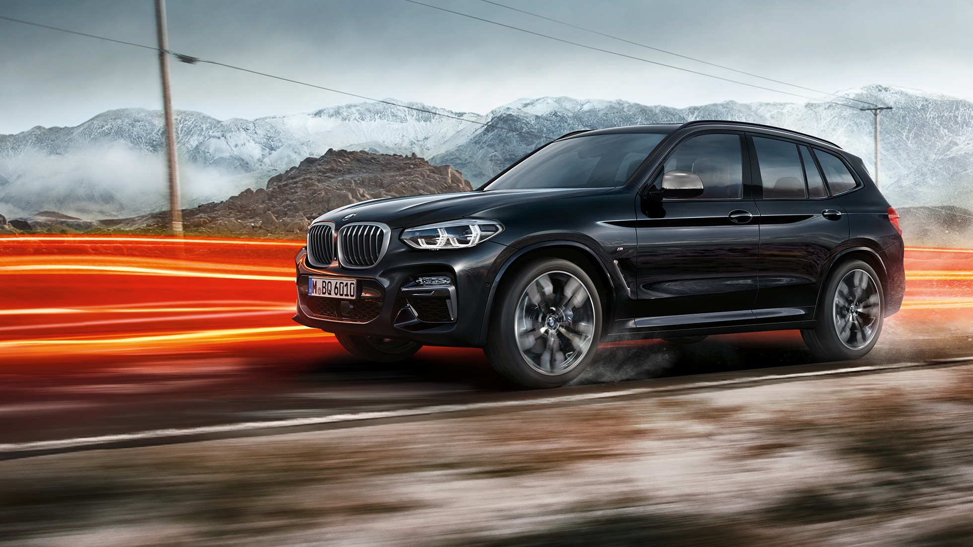 BMW X3 M40i ja BMW X3 M40d, külgvaade. Black Sapphire metallikvärvi BMW X3 M40i ja BMW X3 M40d, sõitmas, välisilme, külgvaade valgusribadega mägimaastiku taustal.