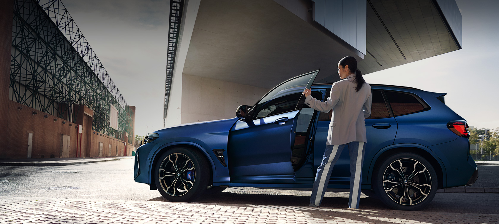 BMW X3 M Competition F97 LCI Facelift 2021, külgvaates seismas BMW X3 M Competition F97 LCI Facelift 2021, toonis BMW Individual Frozen Portimao Blue metallik, külgvaade, seisab avatud ukse ja naismodelliga