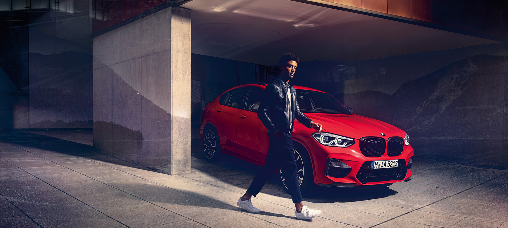 Toronto Red metallikvärvi BMW X4 Competition, välisilme, kolm neljandikku külgvaade koos noormehega.