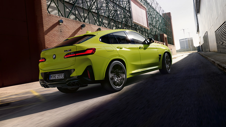 BMW X4 M Competition F98 LCI 2021, kolm neljandikku eestvaade BMW X4 M Competition F98 LCI Facelift 2021, toonis Sao Paulo Yellow, kolm neljandikku eestvaade, sõitmas tehasehoonete vahel