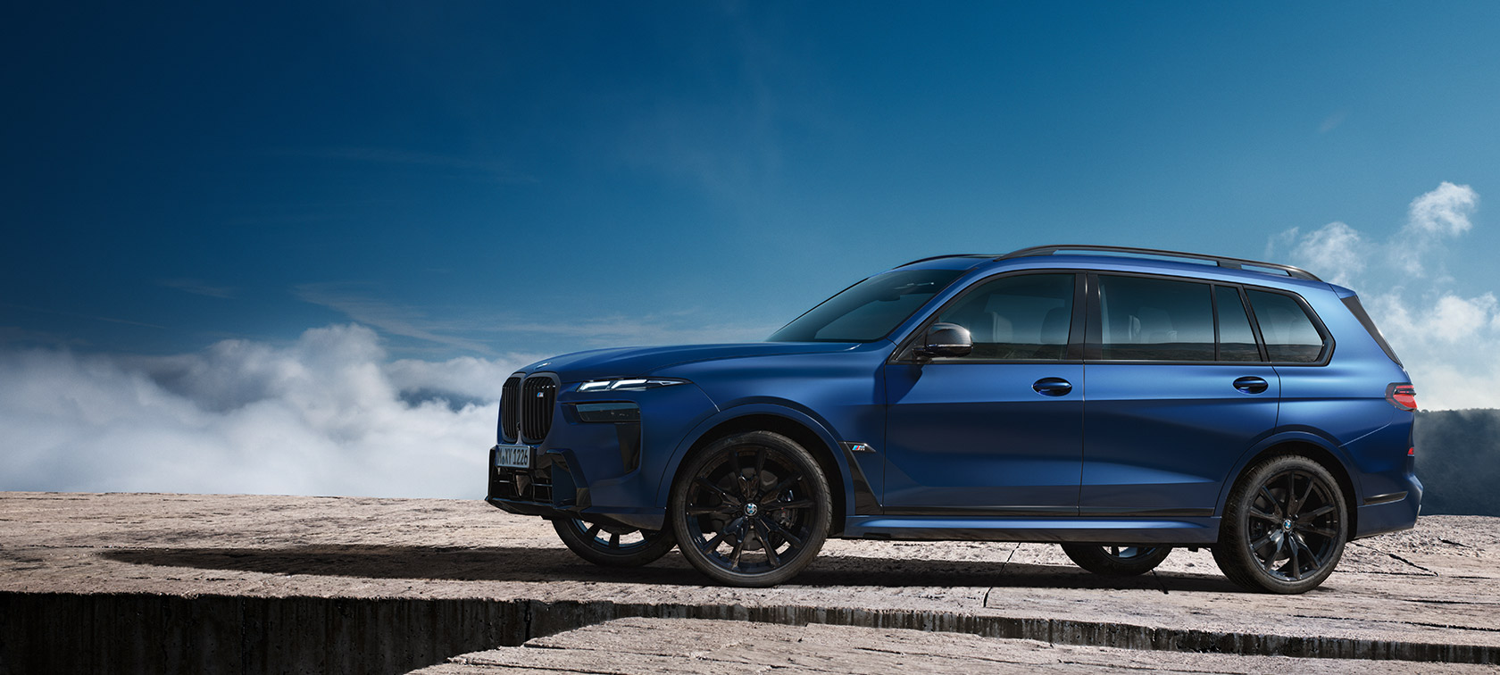 BMW X7 M60i G07 LCI, Frozen Marina Bay Blue, külgvaade seistes mägimaastiku taustal