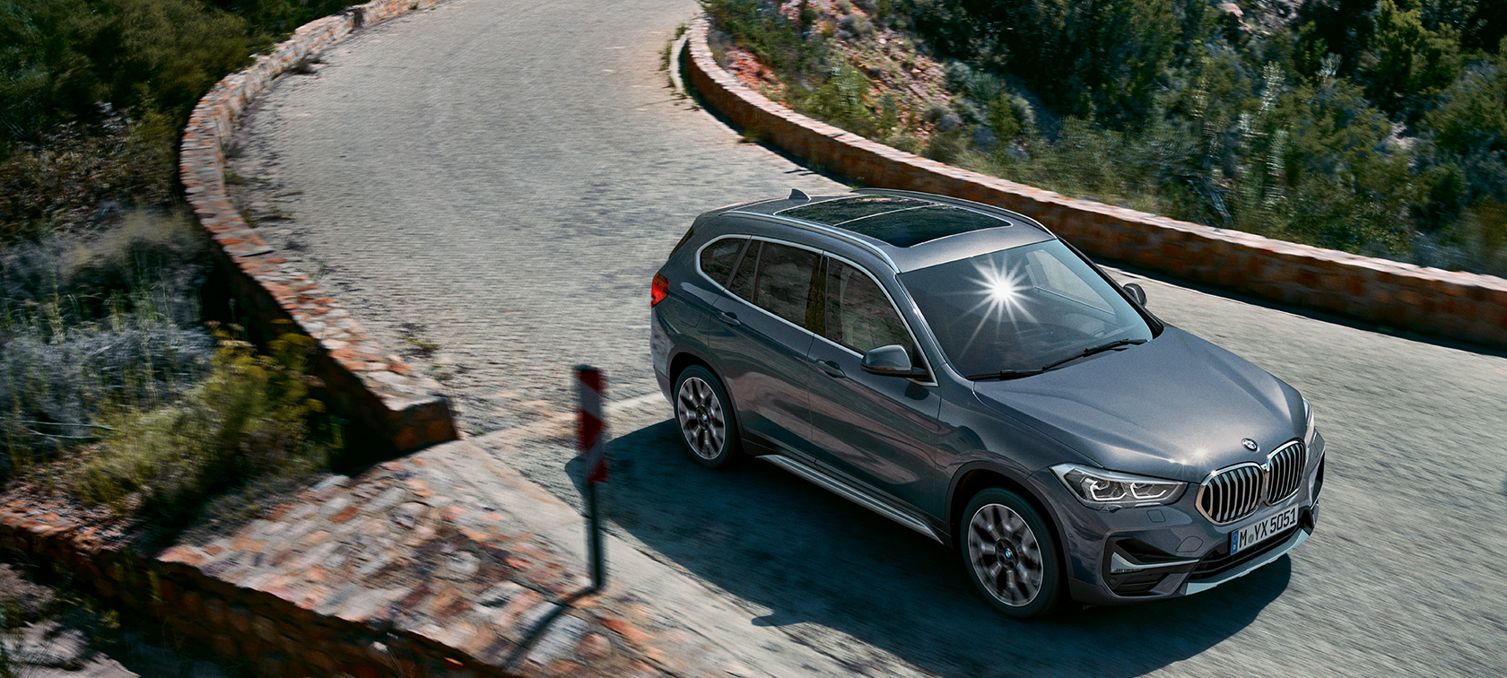 BMW X1, kolm neljandikku eestvaade. BMW X1, kolm neljandikku eestvaade sõitmas mäestiku taustal.