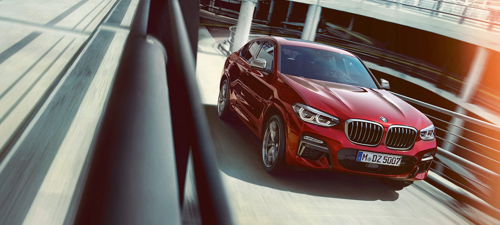 BMW X4 sõitmas parkimismajas BMW X4 G02 2018 toonis Flamenco Red Brilliant Effect, 3/4 külgvaade, sõitmas parkimismajas
