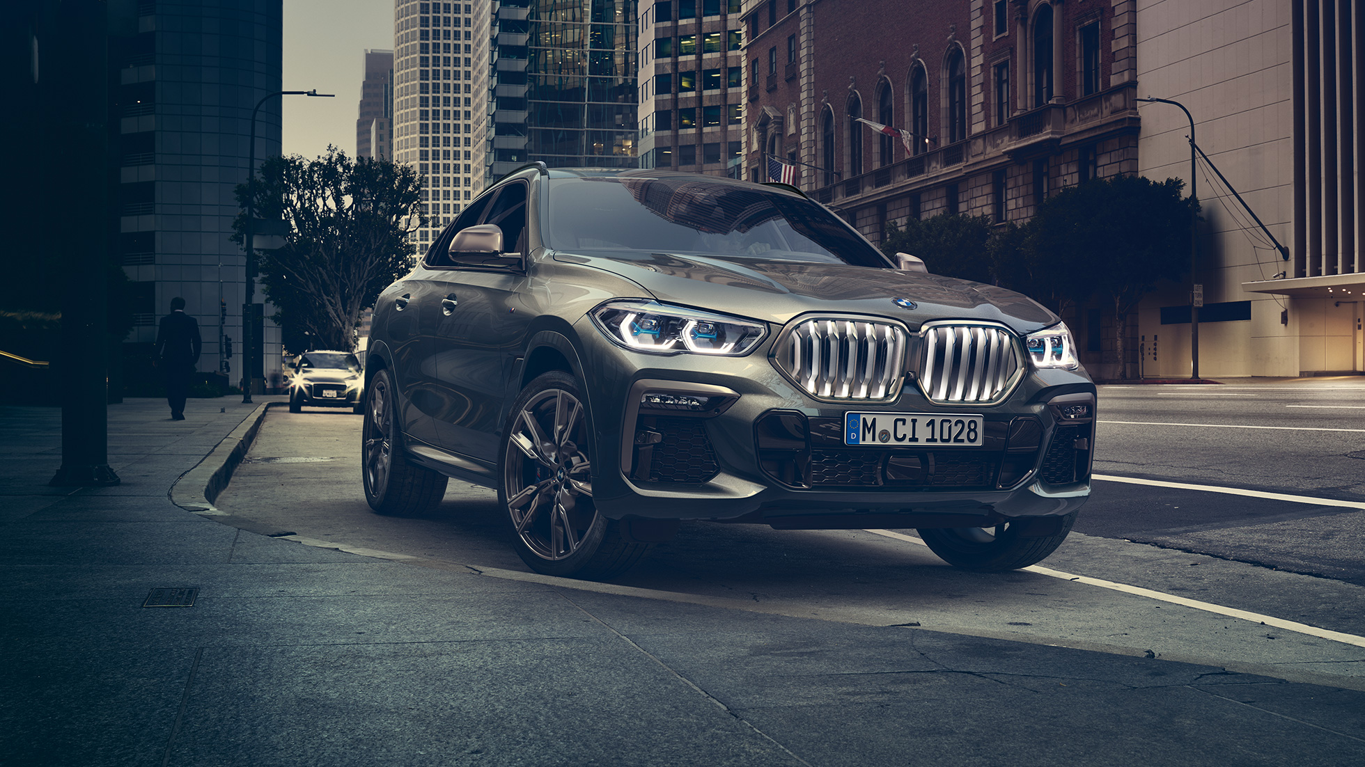 BMW X6 kohanduv M-vedrustus Professional BMW X6 in three-quarter front perspective in front of an urban setting.