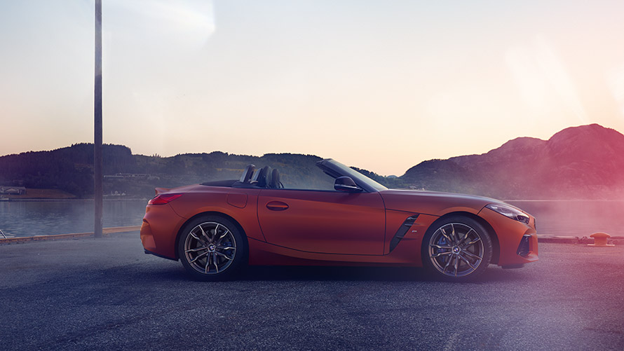 Orange BMW Z4 First Edition standing in curve Orange BMW Z4 First Edition standing in curve in front of mountain landscape